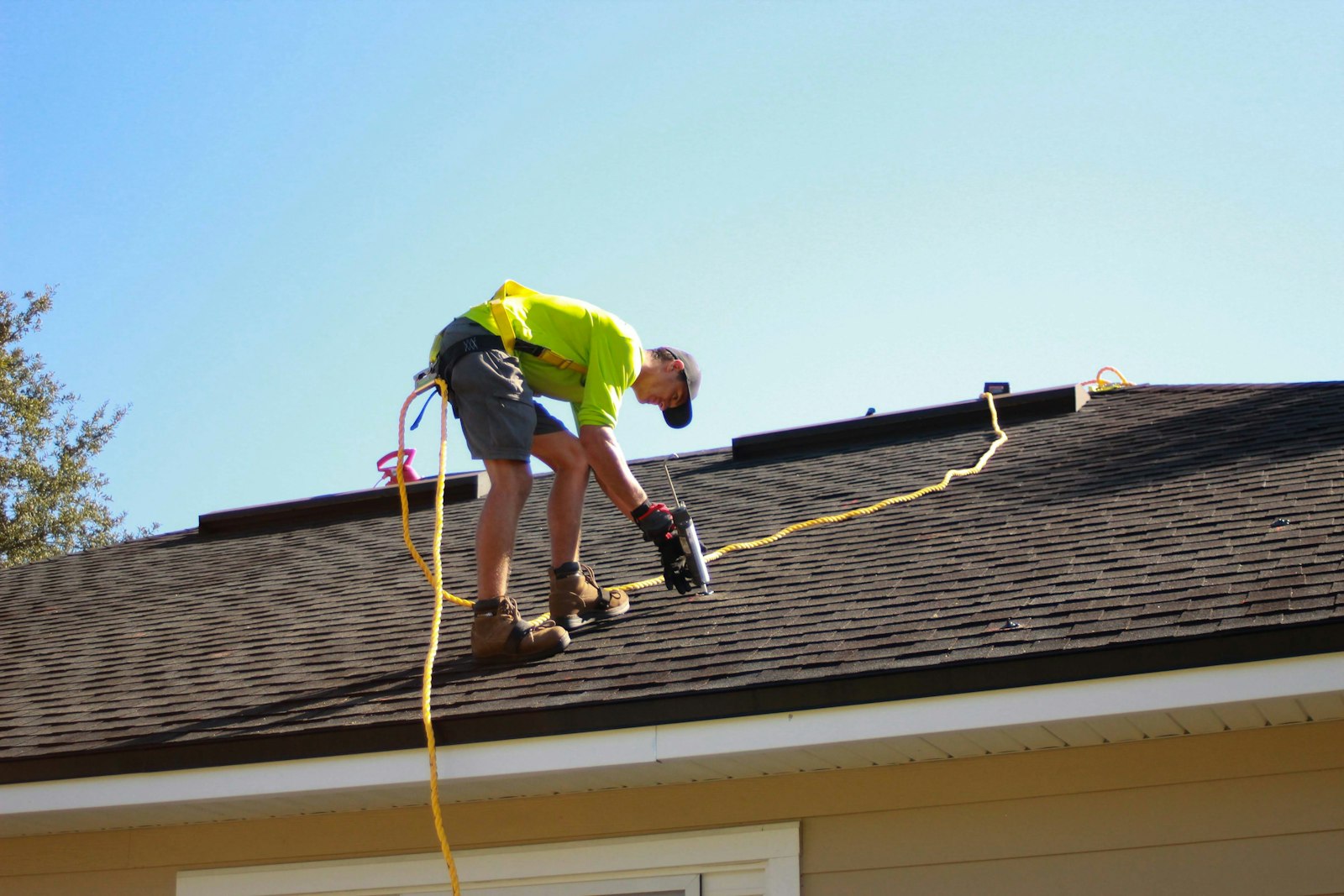 A roofing crew member installing new shingles
